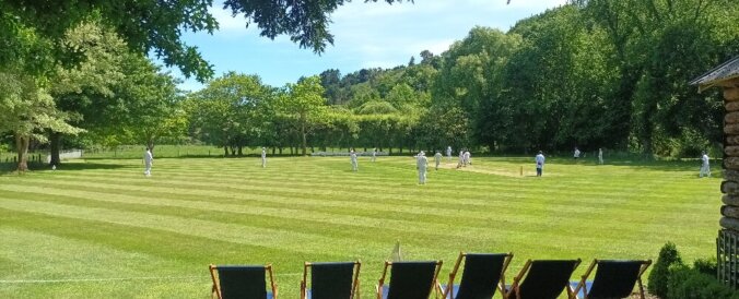 cricket oval, green trees, blue sky, fold-up seats