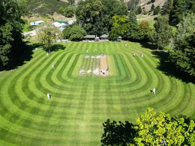 Aerial view of green mown cricket oval, surrounded by trees