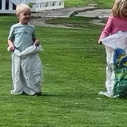 Three children ready to run a sack race on grass